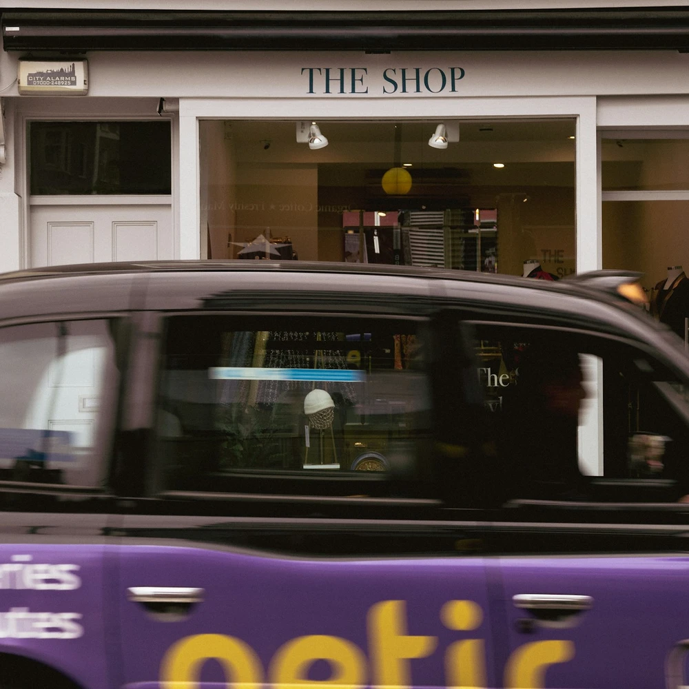 a purple taxi cab driving past a store