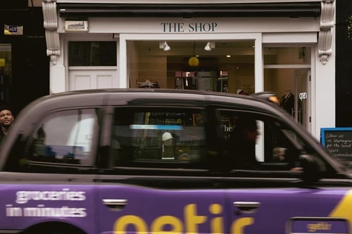 a purple taxi cab driving past a store