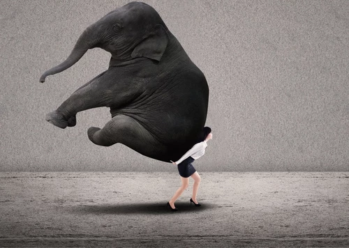 Businesswoman lifting heavy elephant