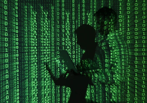 An illustration picture shows projection of binary code on man holding aptop computer in Warsaw