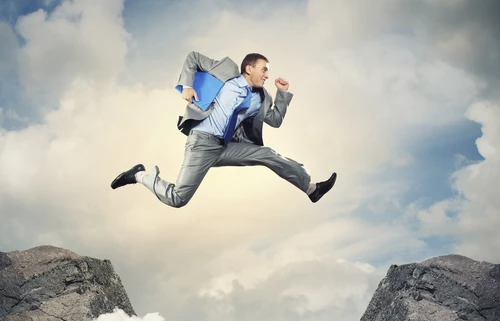 Businessman jumping over gap