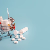 Shopping cart with medicinal pills and scattered tablets.