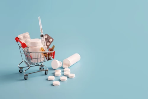 Shopping cart with medicinal pills and scattered tablets.