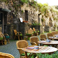 a row of tables and chairs sitting next to a stone wall