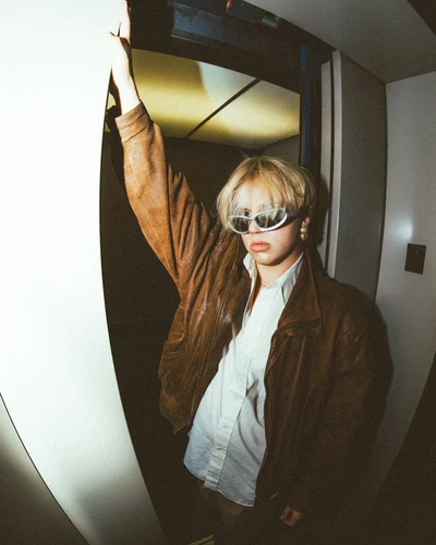 a woman in a brown jacket and sunglasses