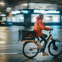 A delivery man on a bike in city centre at night