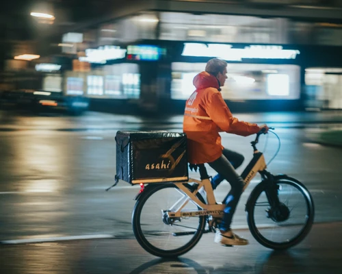 A delivery man on a bike in city centre at night